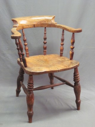 An elm Captains chair with solid seat, raised on turned supports