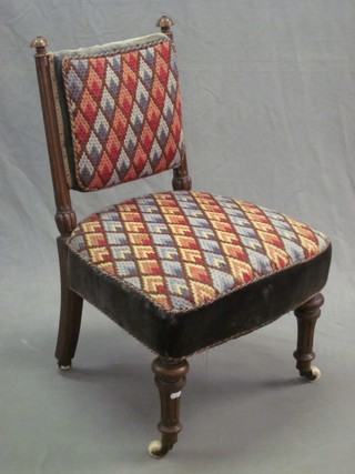 A Victorian walnut nursing chair raised on fluted columns with wool work seat