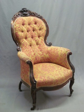 A Victorian carved rosewood show frame armchair with carved cresting rail and button upholstered back, raised on cabriole supports