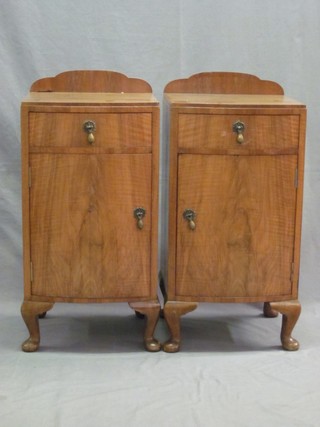 A pair of walnut bow front bedside cabinets fitted a drawer above cupboard, raised on cabriole supports 14"