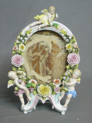 A porcelain floral encrusted frame decorated cherubs (some damage) 10"