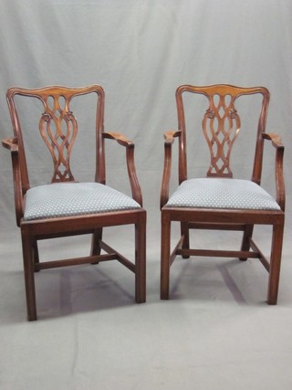 A pair of Chippendale style mahogany dining chairs with upholstered drop in seats, raised on square tapering supports with H framed stretcher