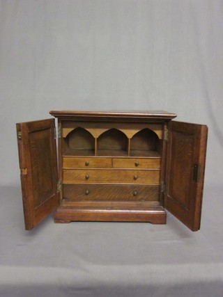 A Victorian oak table top cabinet, the interior fitted pigeon holes and drawers enclosed by panelled doors, raised on a platform base 16"
