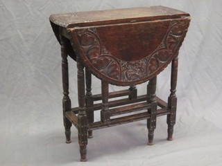 An oval carved oak drop flap gateleg tea table raised on turned and block supports 27"