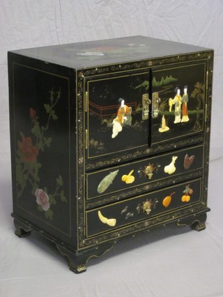 An Eastern lacquered cabinet inlaid hardstones and decorated figures, fitted a cupboard enclosed by panelled doors above 2 long drawers, raised on bracket feet 21"