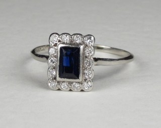 A lady's platinum dress ring set a rectangular blue stone surrounded by diamonds