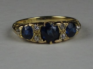 An 18ct gold dress ring set 3 oval cut sapphires supported by diamonds