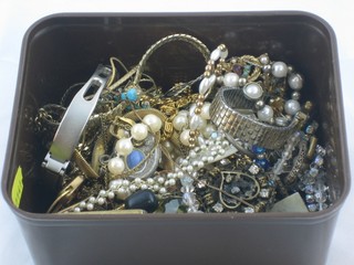 A brown plastic container containing costume jewellery