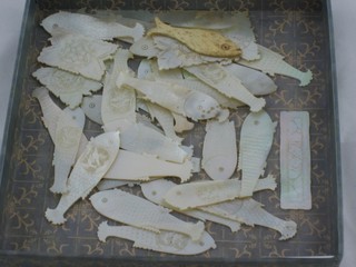 A carved ivory gaming counter in the form of a fish and 31 carved mother of pearl counters in the form of fish and 5 rectangular do.