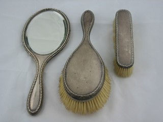 A 3 piece silver backed dressing table set comprising hand mirror, hair brush and clothes brush