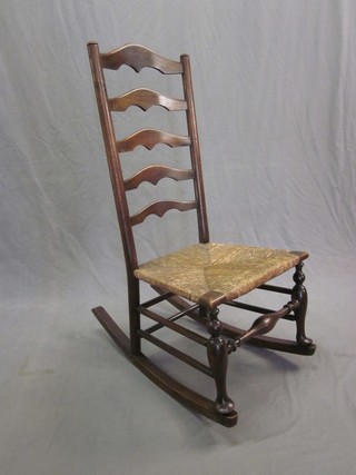 An elm ladder back rocking chair with woven rush seat