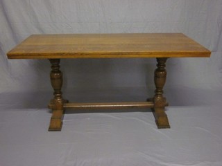 A rectangular honey oak refectory style dining table, raised on turned and block supports with H framed stretcher 61"