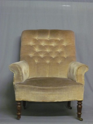 A  Victorian mahogany framed armchair upholstered in mushroom buttoned back material, raised on turned supports