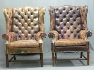 A pair of Georgian style mahogany winged armchairs upholstered in brown leather