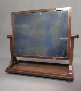 A 19th Century rectangular plate mirror contained in a mahogany swing frame, raised on bun feet 22"