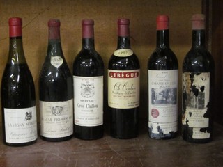 A bottle of 1955 Chateau Chasse-spleen, a bottle of 1957 Lebegue Ch Corbin St Emilion, a bottle of 1959 Beaune Premier Cru, a bottle of 1967 Chateau Gros Caillou, a 1959 bottle of Savigny-Marconnets and 1 other bottle of wine with heavily corroded label