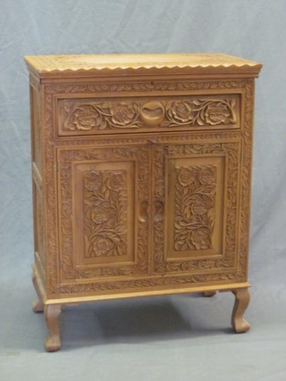 A Burmese carved hardwood cabinet with hinged lid, the base fitted a drawer above a double cupboard, raised on cabriole supports 25"