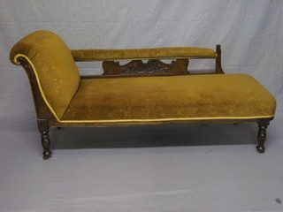 An Edwardian mahogany show frame chaise longue upholstered in brown material and raised on turned supports 59"