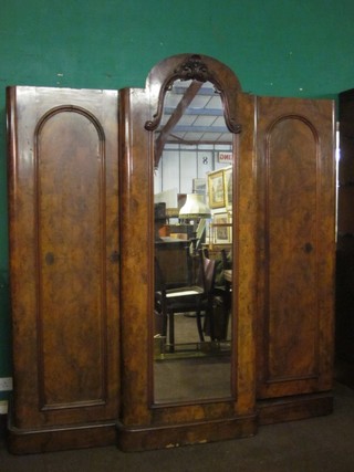 A handsome Victorian figured walnut triple breakfront wardrobe, the centre section enclosed by an arched mirror panelled door  flanked by a pair of cupboards enclosed by an arched panelled  doors 77"