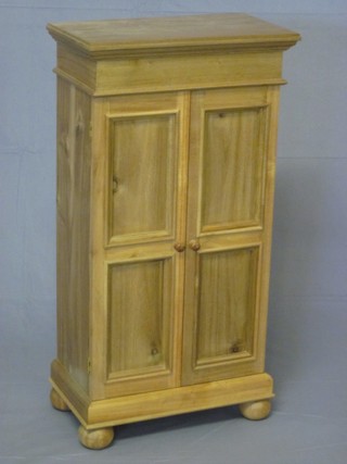 A Victorian style bleached oak "apprentice" cabinet with  moulded cornice, the interior fitted shelves and enclosed by  panelled doors, raised on bun feet 17"