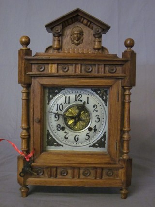 An Edwardian striking bracket clock with square silvered dial and Arabic numerals, contained in a carved oak case 12"