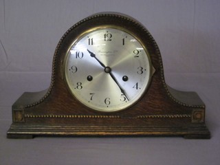 A 1930's 8 day striking mantel clock with silvered dial and Arabic numerals contained in an oak Admirals hat shaped case by  Bravingtons