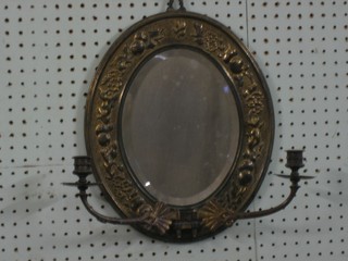 A Victorian oval bevelled plate wall mirror contained in a decorative embossed brass frame with 2 candle sconces 15"