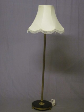 A reeded brass standard lamp raised on a circular black marbled base with bun feet