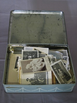 A tin containing a collection of various black and white photographs