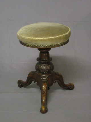 A Victorian carved walnut revolving adjustable piano stool, raised on a tripod base