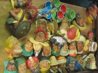 A collection of various plaster wall masks in the form of heads together with a small coffee set