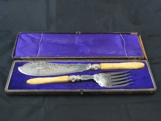 A pair of pierced silver plated fish servers with carved ivory  handles, cased
