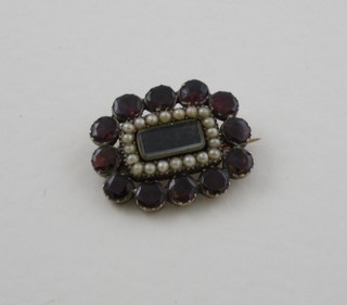 A 19th Century gilt metal mourning brooch with woven hair  panel surrounded by garnets