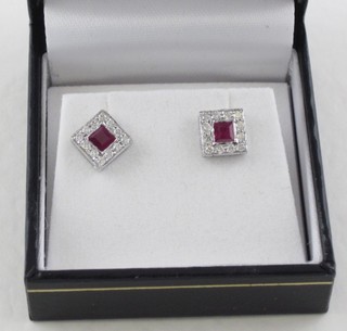 A pair of earrings set square cut rubies surrounded by diamonds
