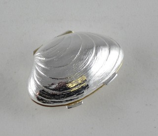 A modern silver pill box in the form of a clam shell