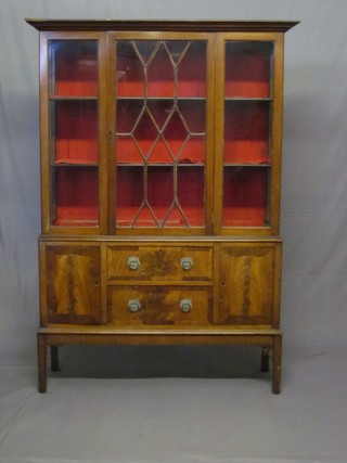 A Georgian style mahogany display cabinet, the upper section with moulded cornice fitted shelves enclosed by astragal glazed panelled doors, the base fitted 2 drawers flanked by a pair of cupboards raised on square tapering supports 49"