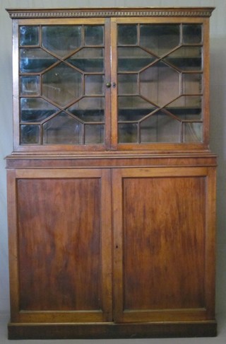 A Victorian mahogany bookcase on cabinet, the upper section with moulded and dentil cornice fitted adjustable shelves enclosed by astragal glazed panelled doors, the base fitted a cupboard enclosed by panelled doors, raised on a platform base 48"