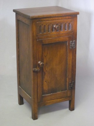 A carved oak bedside cabinet fitted a drawer enclosed by a panelled cupboard with arcaded decoration 13"