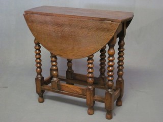 A honey oak drop flap gateleg tea table, raised on bobbin turned supports 27"