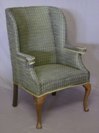 A beech framed tub back winged armchair, raised on cabriole supports upholstered in green material