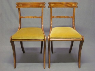 A set of 7 Regency style inlaid rosewood bar back dining chairs with upholstered seats, raised on sabre supports