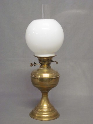A brass oil lamp with opaque white glass shade