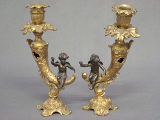 A pair of gilt metal candlesticks decorated cherubs by cornucopias, 1 bent, 8"