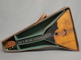 A 3 stringed Balalaika, musical instrument, with a triangular shaped body, contained in a leather carrying case