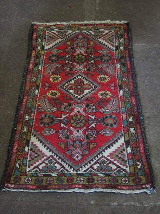 An Eastern red ground rug with lozenge shaped medallion and geometric decoration 45" x 26"