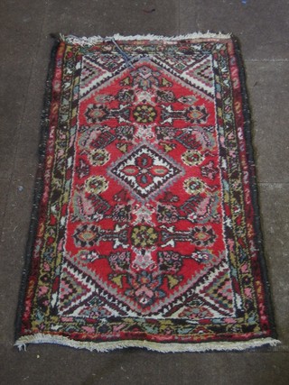 A red ground Eastern rug with diamond shaped medallion and all-over geometric design 43" x 26"