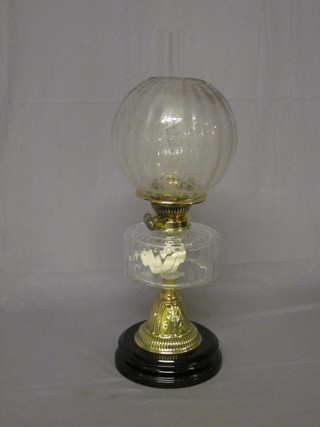 A brass oil lamp with clear glass reservoir and etched glass shade with clear glass chimney