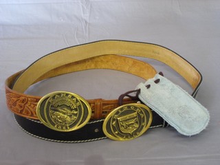 A leather belt with an American brass buckle marked Arizona and 1 other marked Kansas