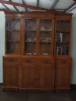 A Georgian style yew breakfront library bookcase with moulded and dentil cornice, the interior fitted adjustable shelves enclosed by astragal glazed panelled doors, the base fitted 4 short drawers above 4 cupboards enclosed by a panelled door, raised on bracket feet 71"