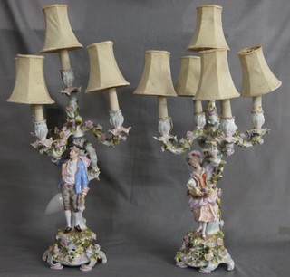 A pair of 19th/20th Century porcelain 5 light candelabrum converted for use as electric table lamps and supported by a figure of a lady and gentleman, some chips and f and r, 22" high